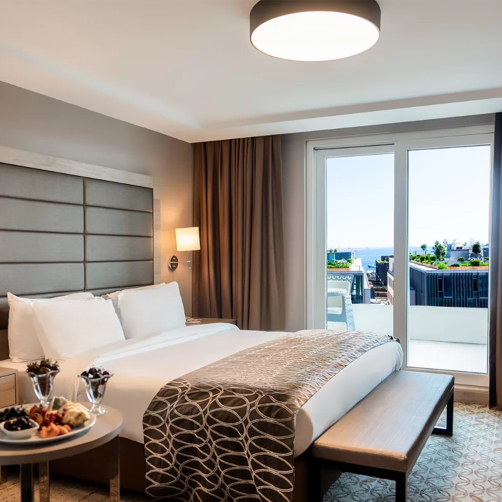 Deluxe room: bed and glass door opening onto the terrace